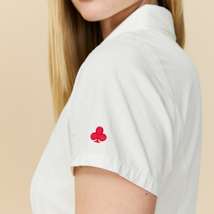 White shirt with a red club emblem on a beige background
